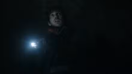Austin Abrams está en una alcantarilla con una linterna mirando a un monstruo en Resident Evil