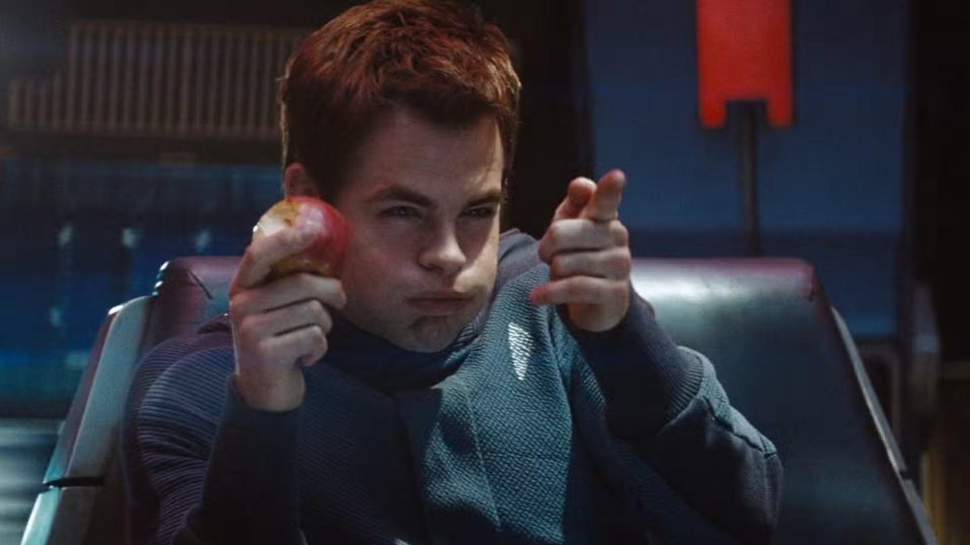Chris Pine como James Kirk en Star Trek de 2009. Está comiendo una manzana y haciendo una pistola con la otra mano.