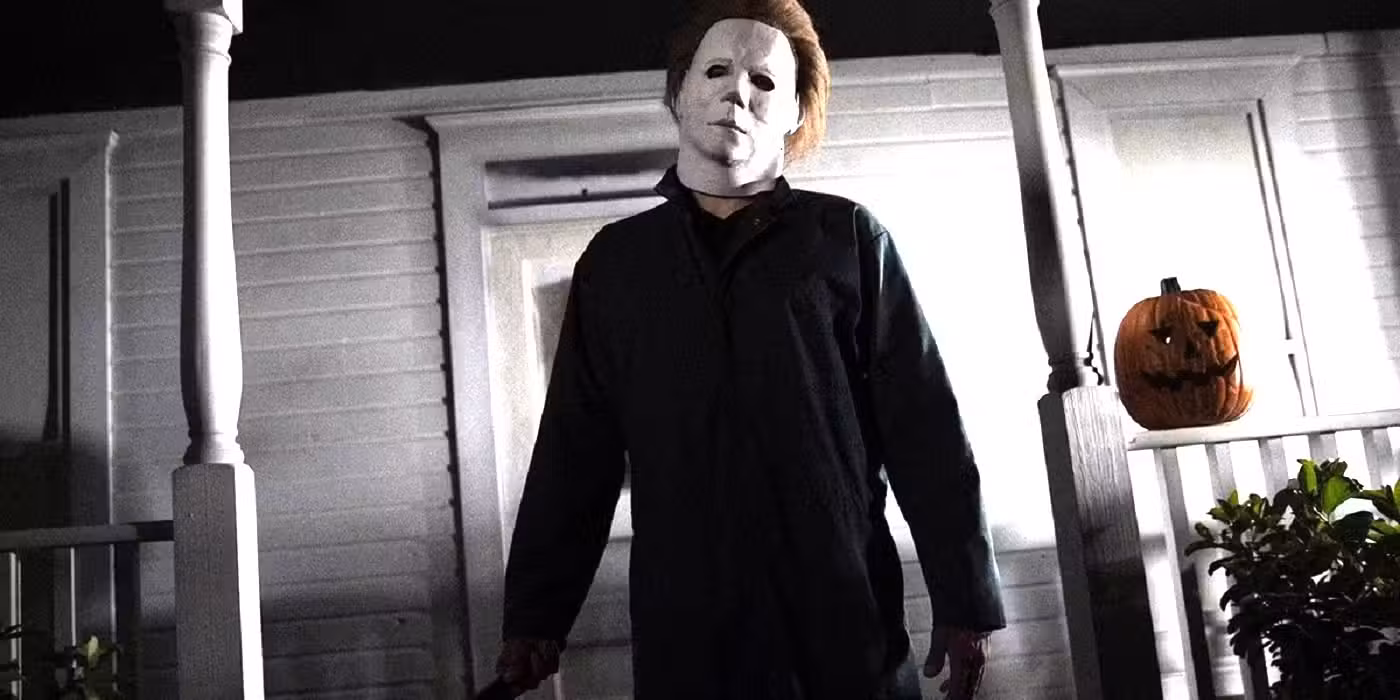 Michael Meyers en Halloween parado en un porche junto a una calabaza