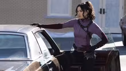 Hailee Steinfeld como Kate Bishop con su mano encima de un auto en Hawkeye