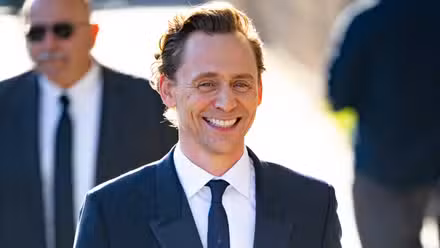 Tom Hiddleston con traje sonriendo ampliamente